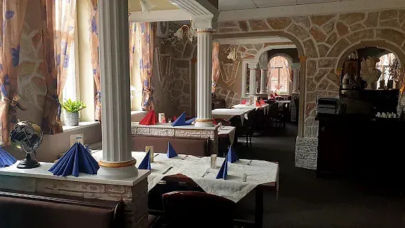 Gastraum des Restaurant Herkules mit weißen Säulen, Steinbögen und gedeckten Tischen